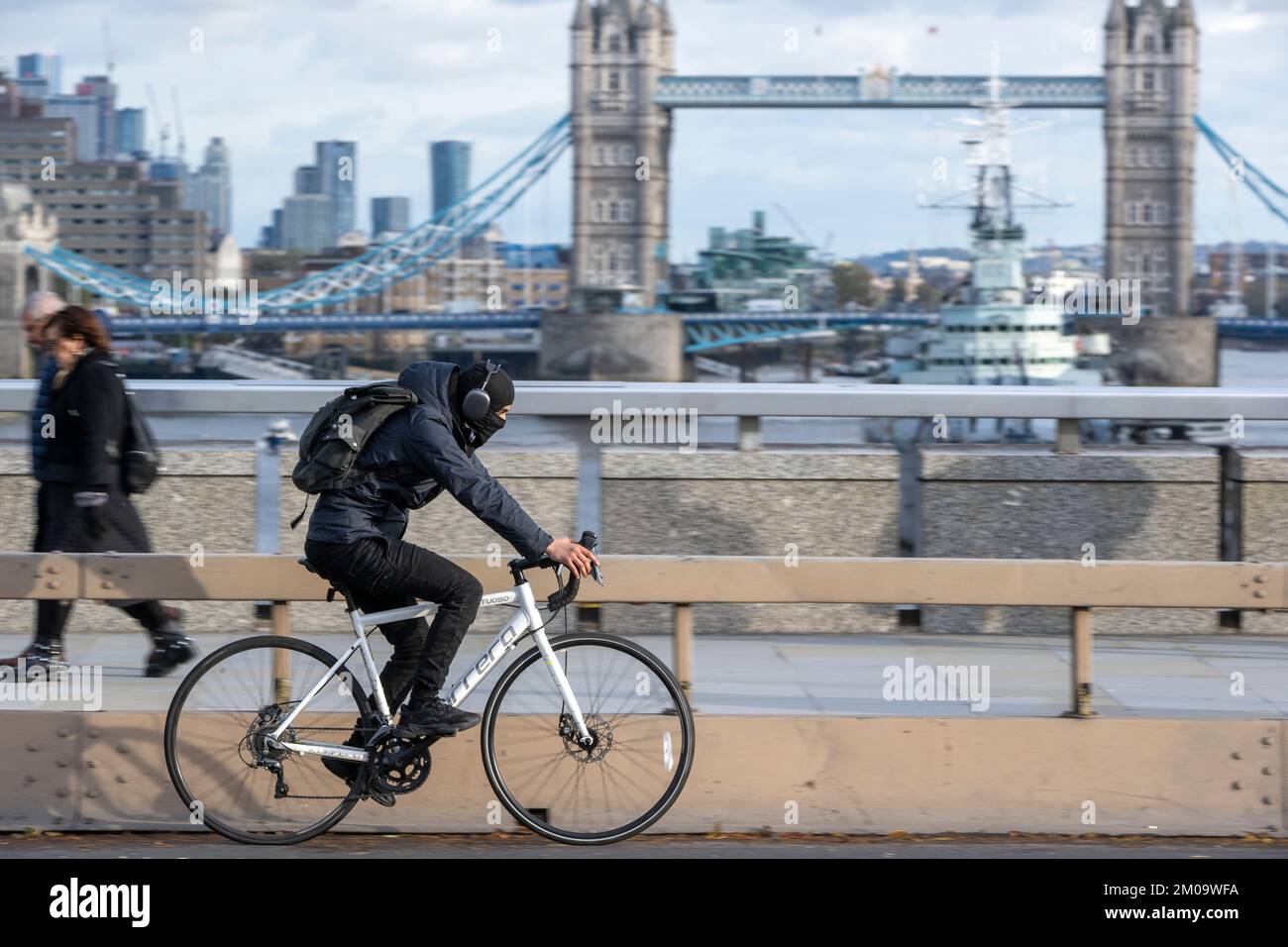 Un uomo che si collega in bicicletta durante l'ora di punta attraverso il London Bridge, Londra, Regno Unito. 17 Nov 2022 Foto Stock