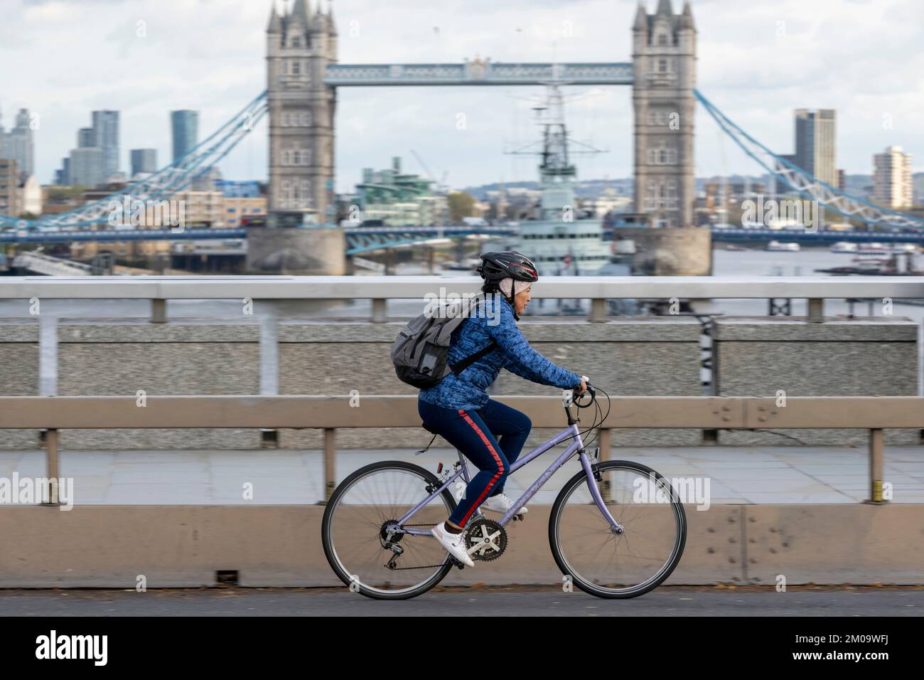 Una donna che si collega in bicicletta durante l'ora di punta attraverso il London Bridge, Londra, Regno Unito. 17 Nov 2022 Foto Stock
