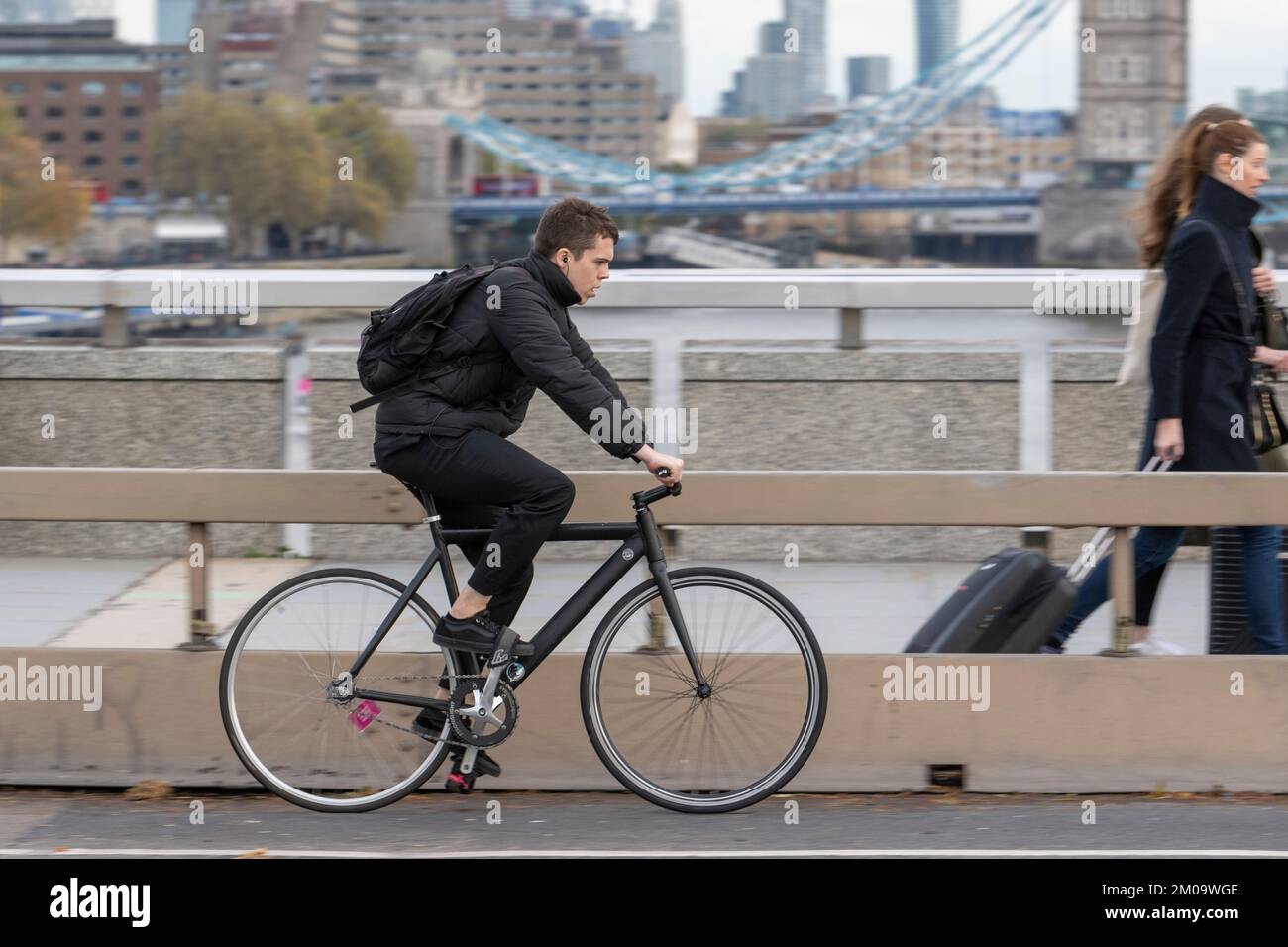 Un uomo che si collega in bicicletta durante l'ora di punta attraverso il London Bridge, Londra, Regno Unito. 17 Nov 2022 Foto Stock