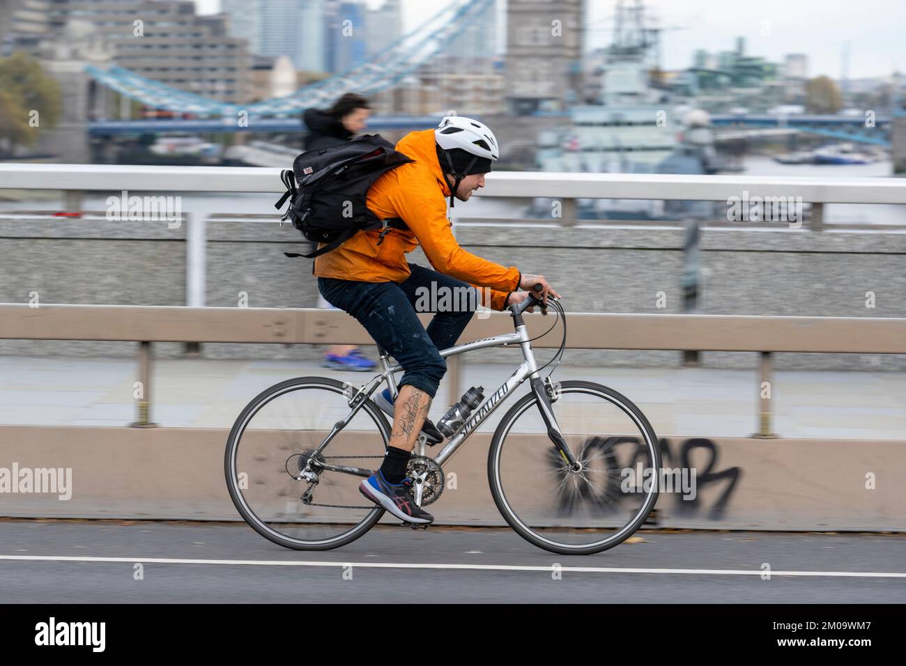 Un uomo che si collega in bicicletta durante l'ora di punta attraverso il London Bridge, Londra, Regno Unito. 17 Nov 2022 Foto Stock