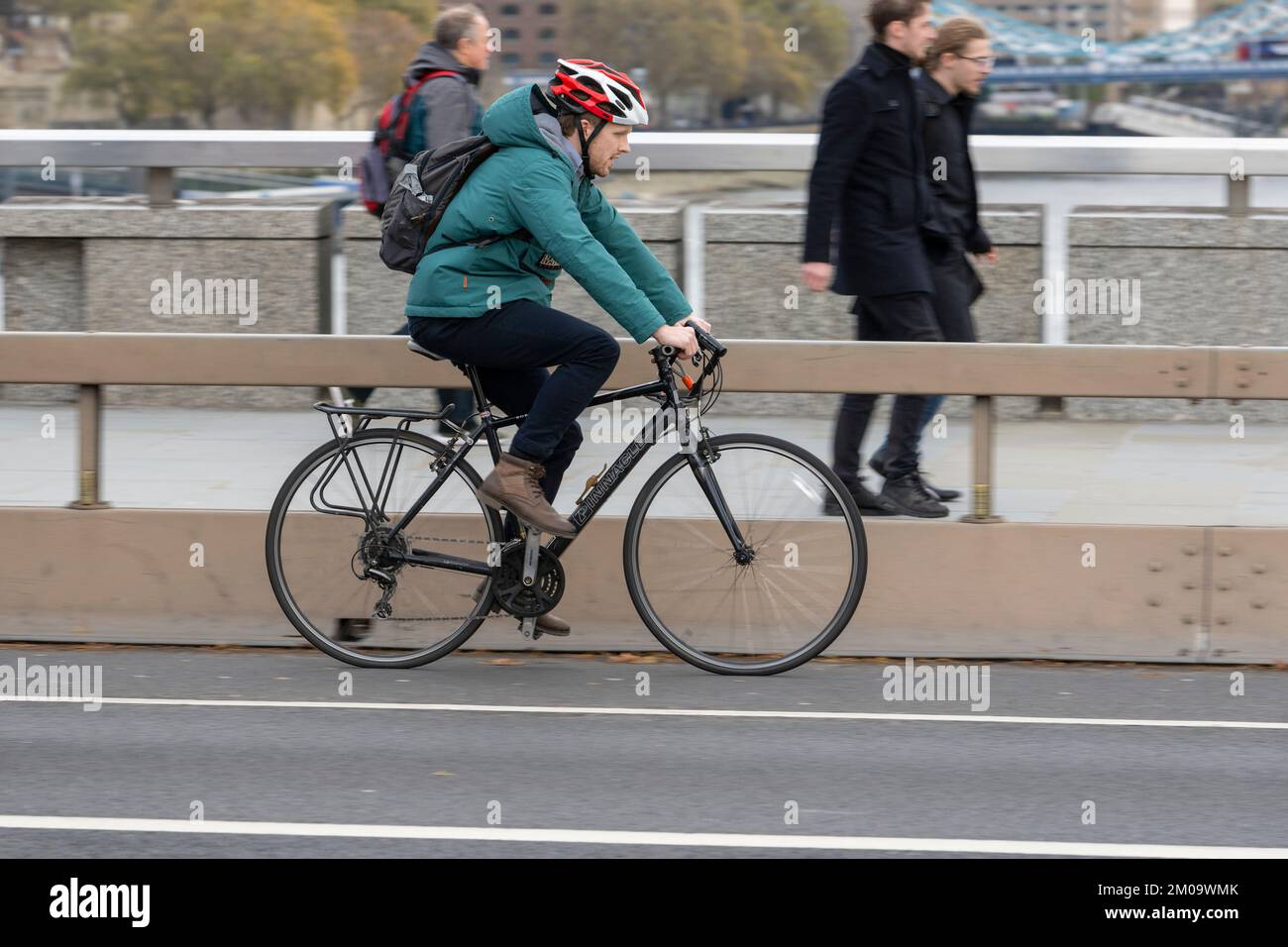 Un uomo che si collega in bicicletta durante l'ora di punta attraverso il London Bridge, Londra, Regno Unito. 17 Nov 2022 Foto Stock