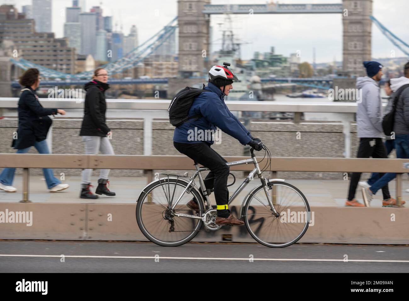 Un uomo che si collega in bicicletta durante l'ora di punta attraverso il London Bridge, Londra, Regno Unito. 17 Nov 2022 Foto Stock