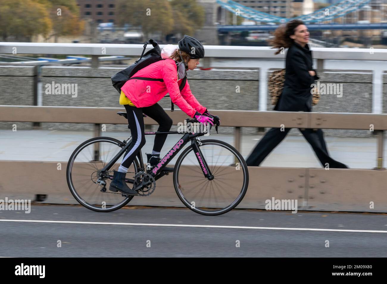 Una donna che si collega in bicicletta durante l'ora di punta attraverso il London Bridge, Londra, Regno Unito. 17 Nov 2022 Foto Stock