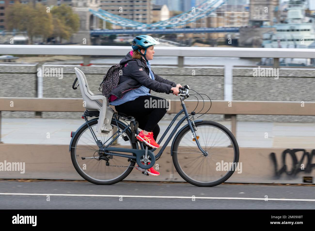 Una donna che si collega in bicicletta durante l'ora di punta attraverso il London Bridge, Londra, Regno Unito. 17 Nov 2022 Foto Stock