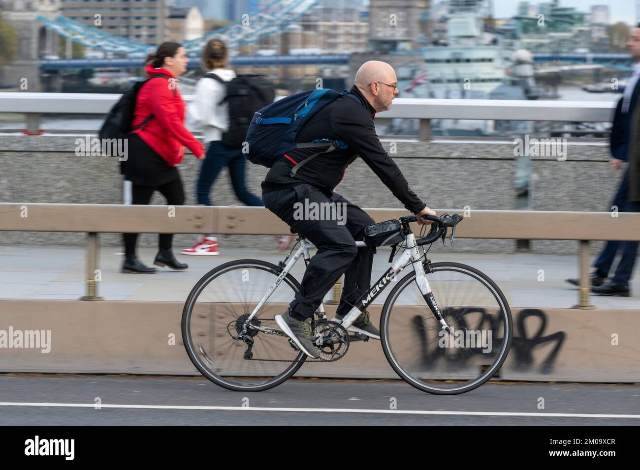 Un uomo che si collega in bicicletta durante l'ora di punta attraverso il London Bridge, Londra, Regno Unito. 17 Nov 2022 Foto Stock