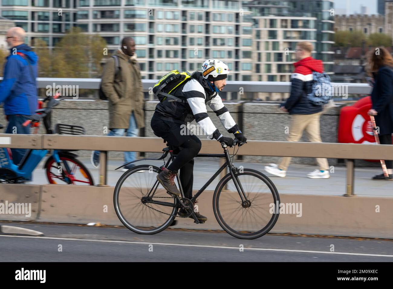 Un uomo che si collega in bicicletta durante l'ora di punta attraverso il London Bridge, Londra, Regno Unito. 17 Nov 2022 Foto Stock