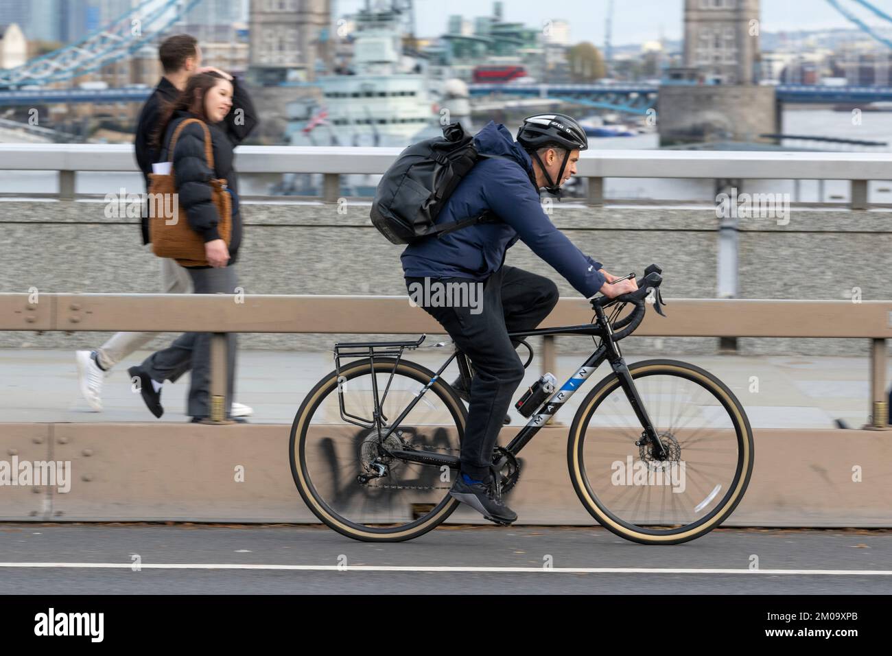 Un uomo che si collega in bicicletta durante l'ora di punta attraverso il London Bridge, Londra, Regno Unito. 17 Nov 2022 Foto Stock