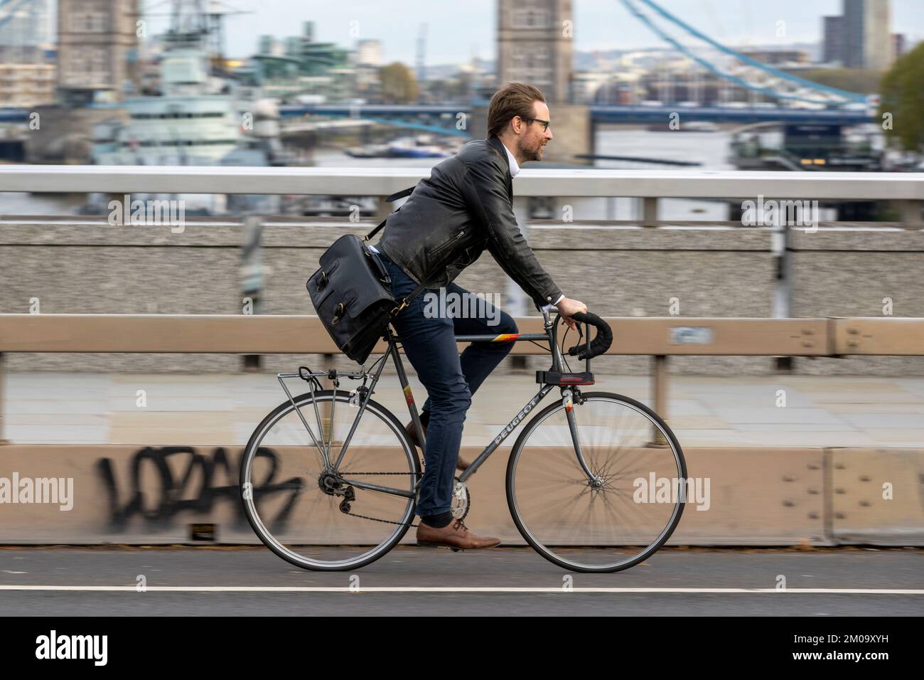 Un uomo che si collega in bicicletta durante l'ora di punta attraverso il London Bridge, Londra, Regno Unito. 17 Nov 2022 Foto Stock