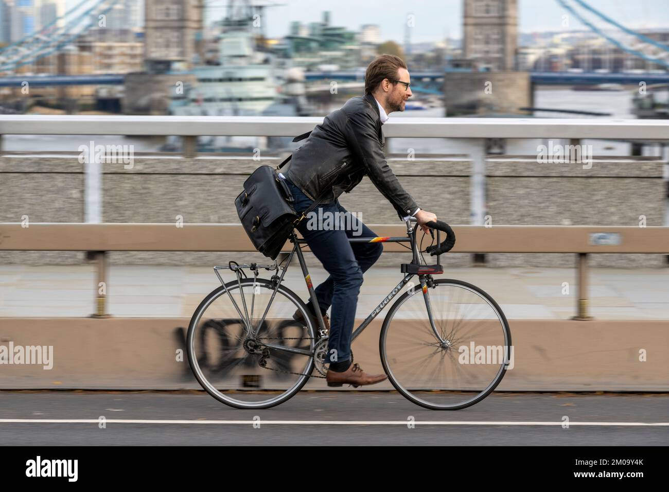 Un uomo che si collega in bicicletta durante l'ora di punta attraverso il London Bridge, Londra, Regno Unito. 17 Nov 2022 Foto Stock