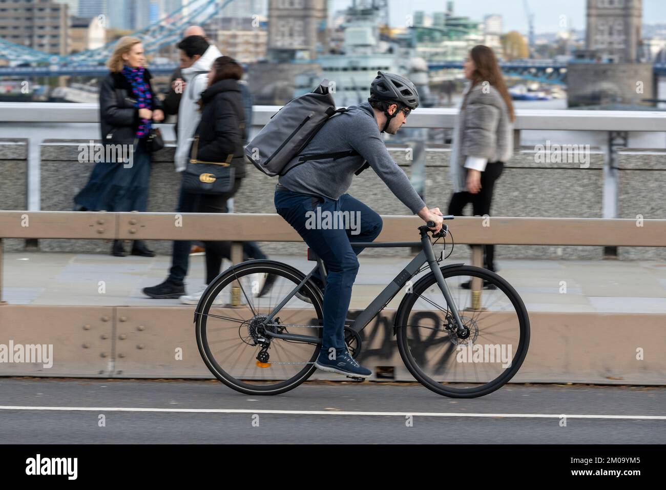 Un uomo che si collega in bicicletta durante l'ora di punta attraverso il London Bridge, Londra, Regno Unito. 17 Nov 2022 Foto Stock