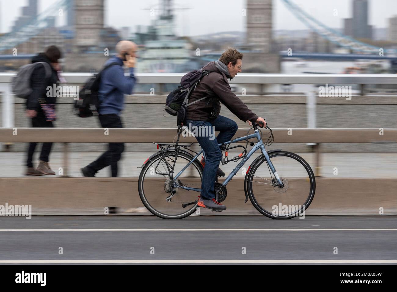 Un uomo che si collega in bicicletta durante l'ora di punta attraverso il London Bridge, Londra, Regno Unito. 16 Nov 2022 Foto Stock