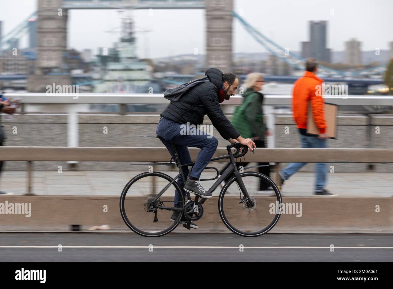 Un uomo che si collega in bicicletta durante l'ora di punta attraverso il London Bridge, Londra, Regno Unito. 16 Nov 2022 Foto Stock