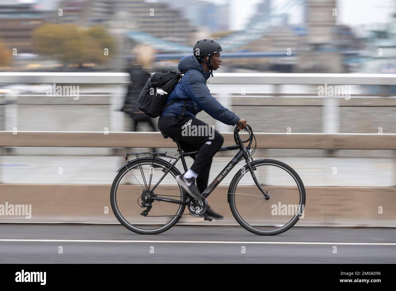 Un uomo che si collega in bicicletta durante l'ora di punta attraverso il London Bridge, Londra, Regno Unito. 16 Nov 2022 Foto Stock