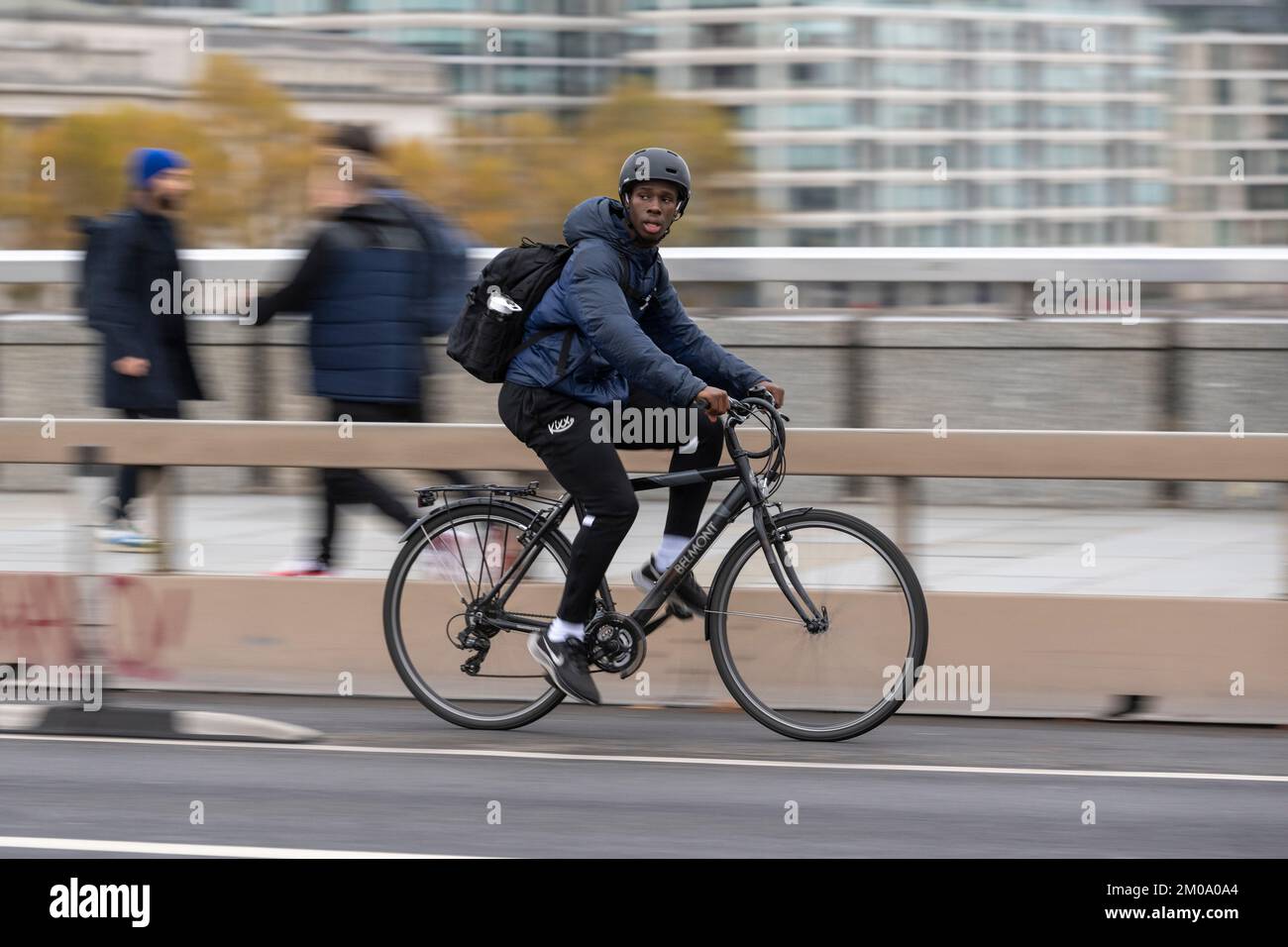 Un uomo che si collega in bicicletta durante l'ora di punta attraverso il London Bridge, Londra, Regno Unito. 16 Nov 2022 Foto Stock