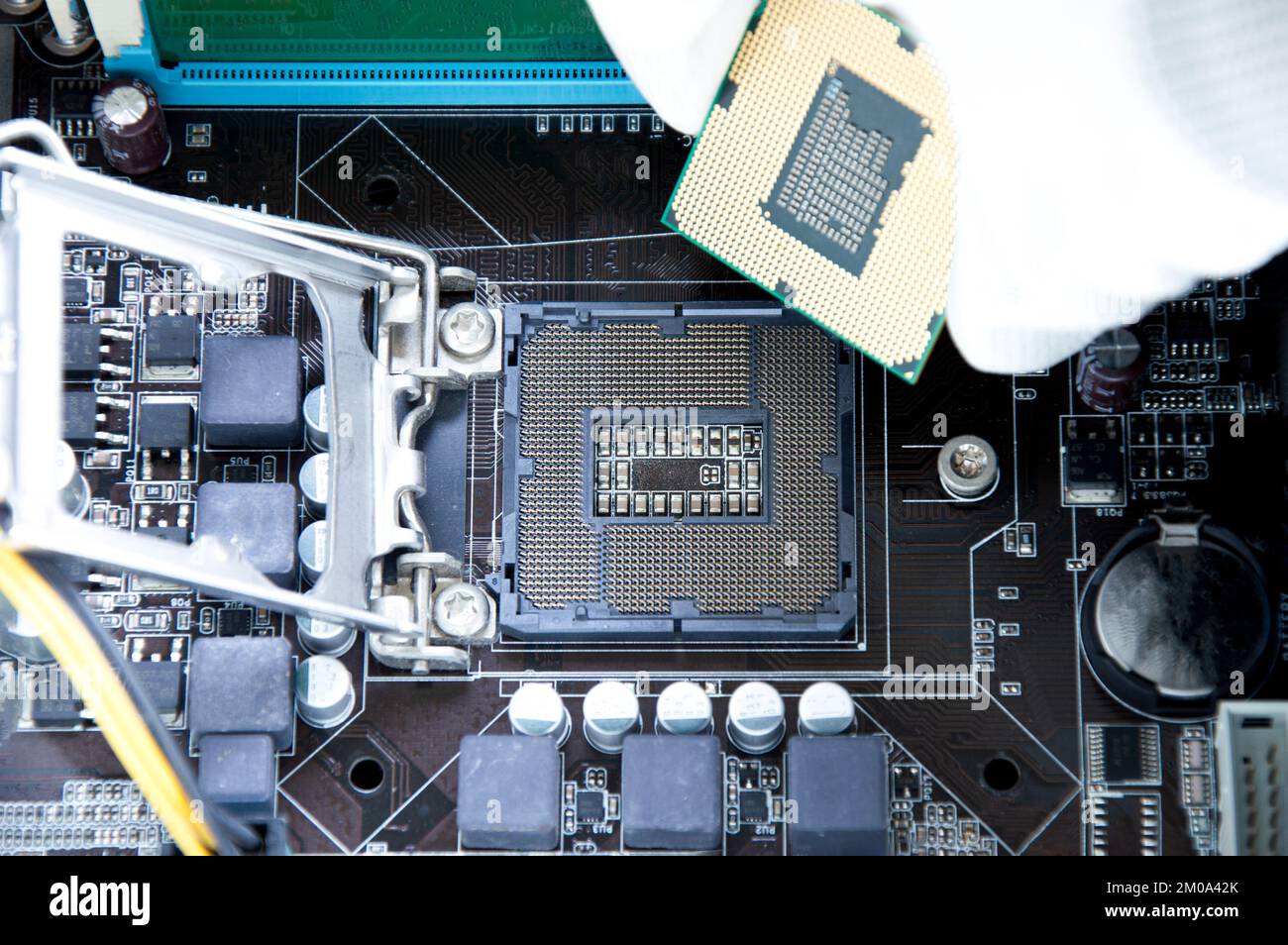 Vista dall'alto della scheda madre e del tecnico sull'inserimento del chip della CPU. Foto Stock
