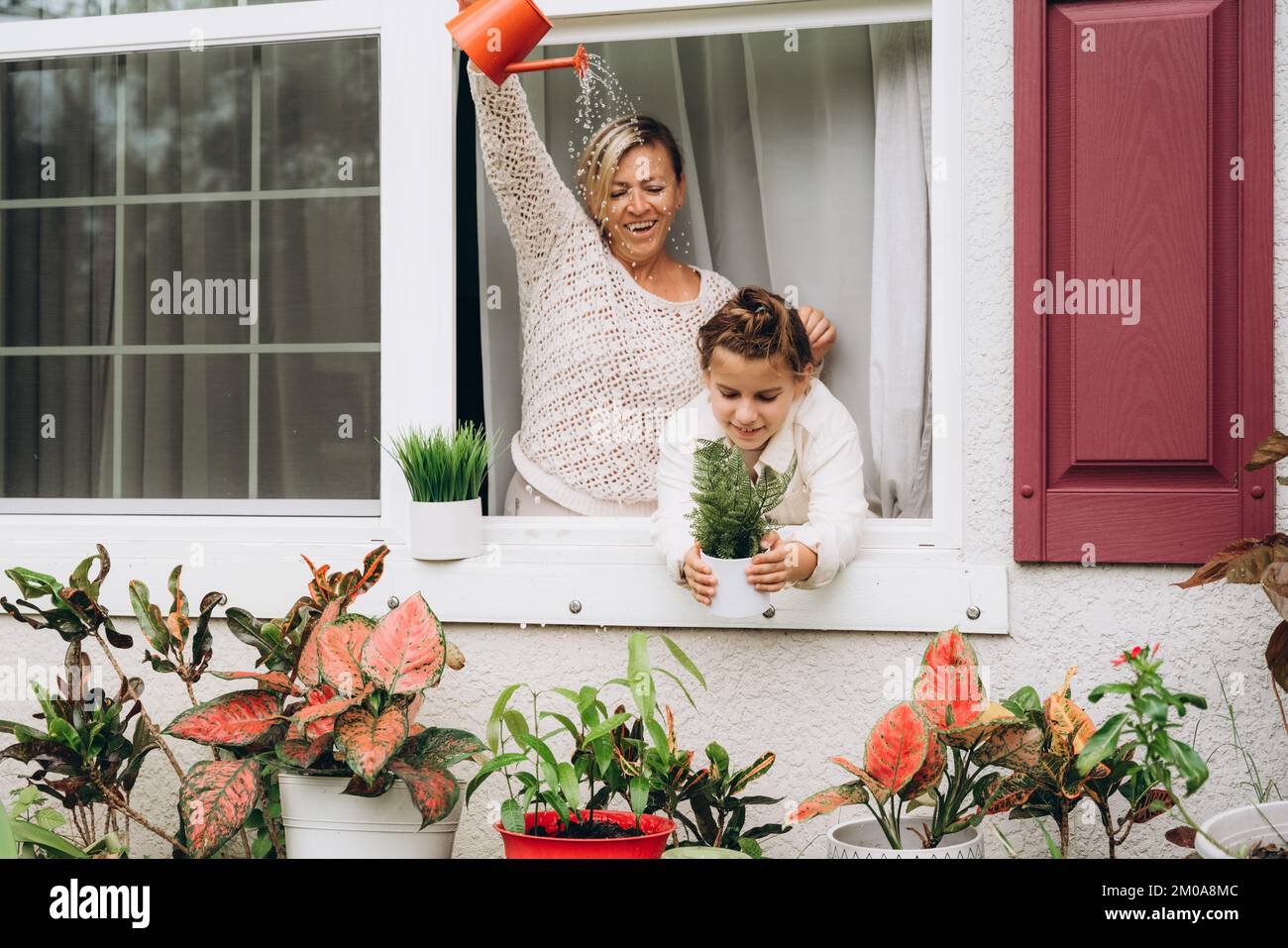 Ragazza con mamma che innaffia le piante da un annaffiatoio Foto Stock