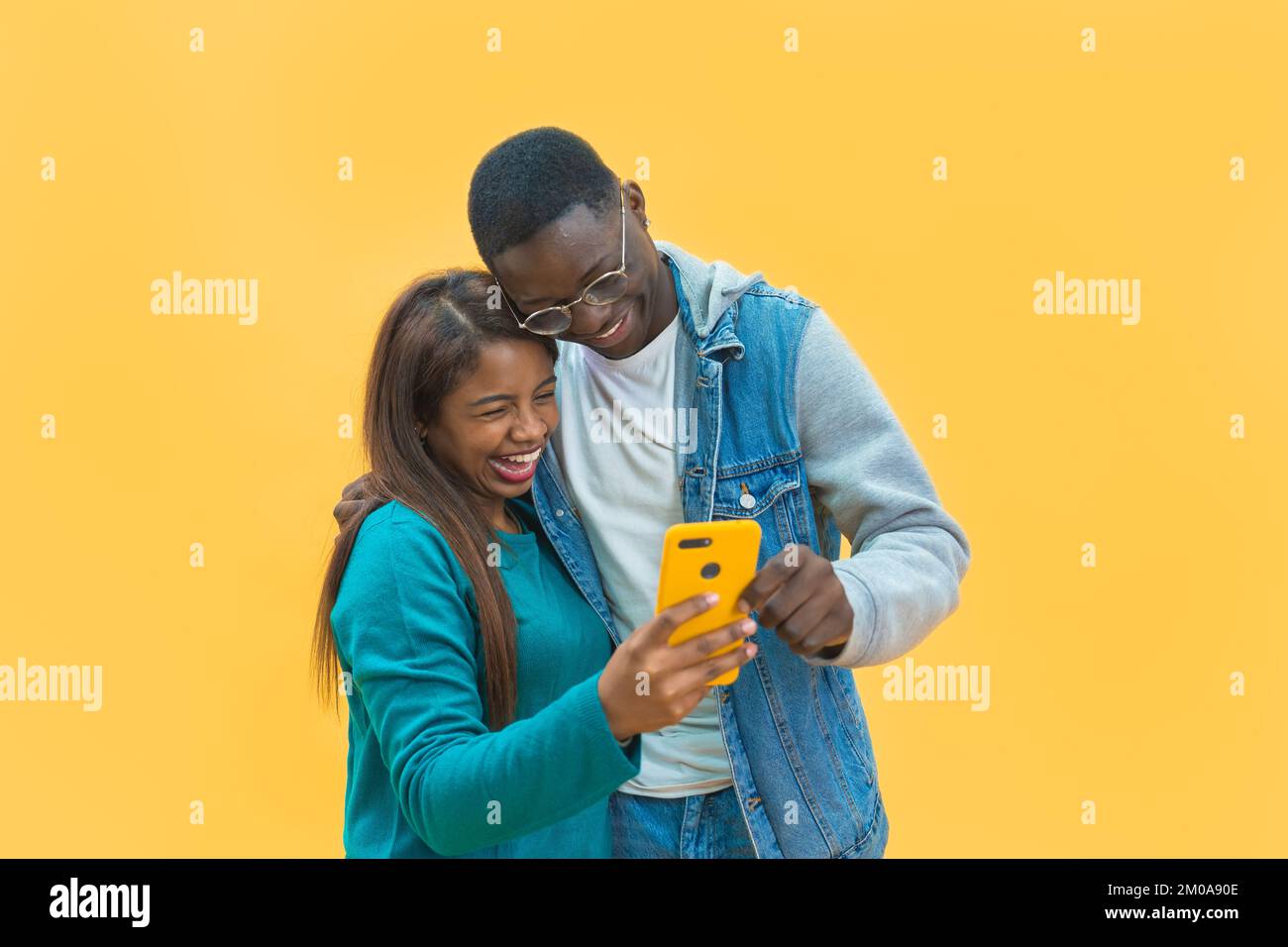 Eccitato coppia nera guardando il telefono cellulare schermo giallo studio sfondo Foto Stock
