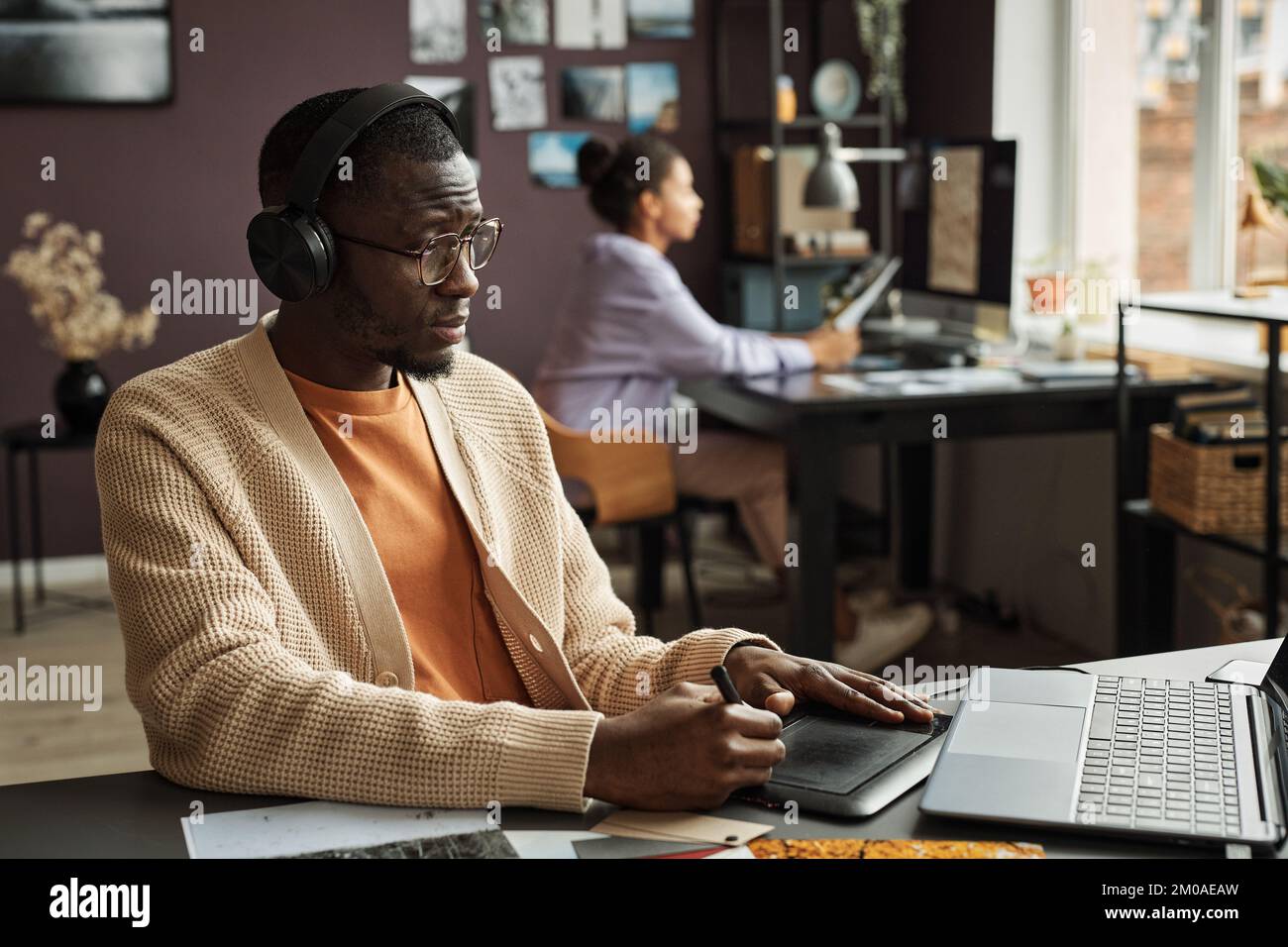 Designer grafico creativo che ascolta la musica mentre disegna su un tablet grafico Foto Stock