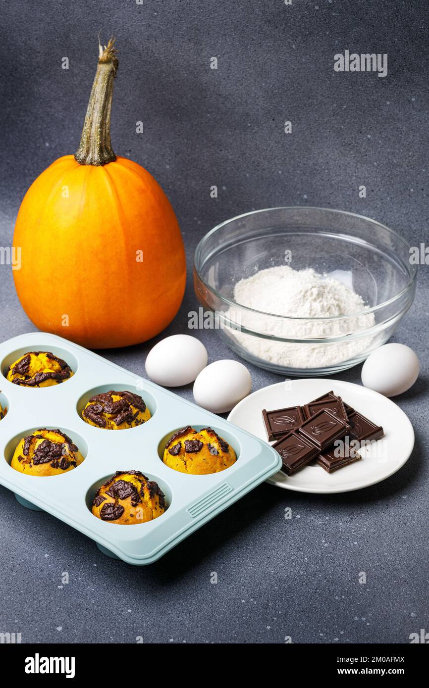 Muffin di zucca cotti al forno nella muffa di silicone al tavolo con ingredienti. Forno muffin sfondo cucina casalinga Foto Stock