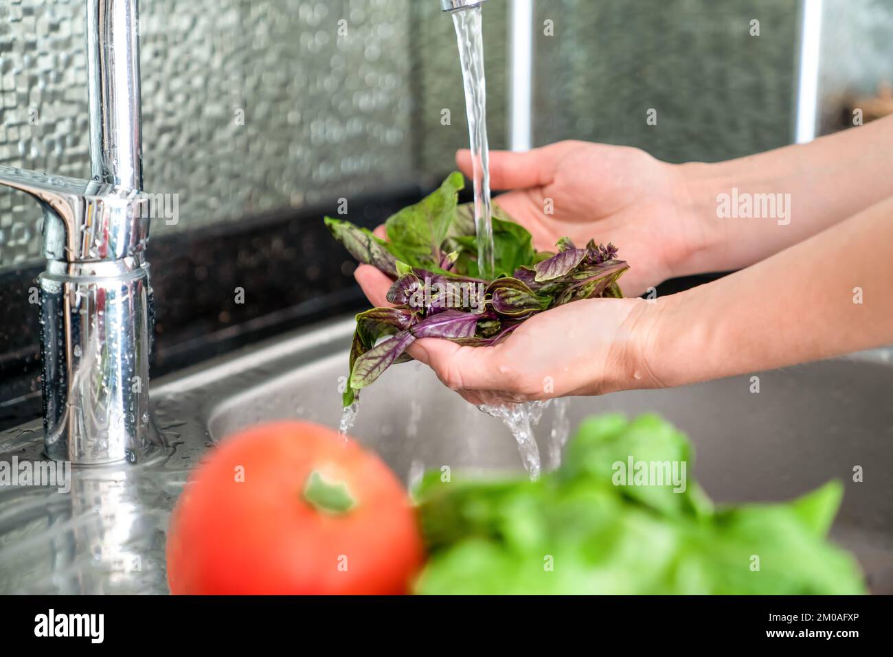 La donna lava le verdure fresche sopra il lavandino, primo piano, senza una faccia Foto Stock