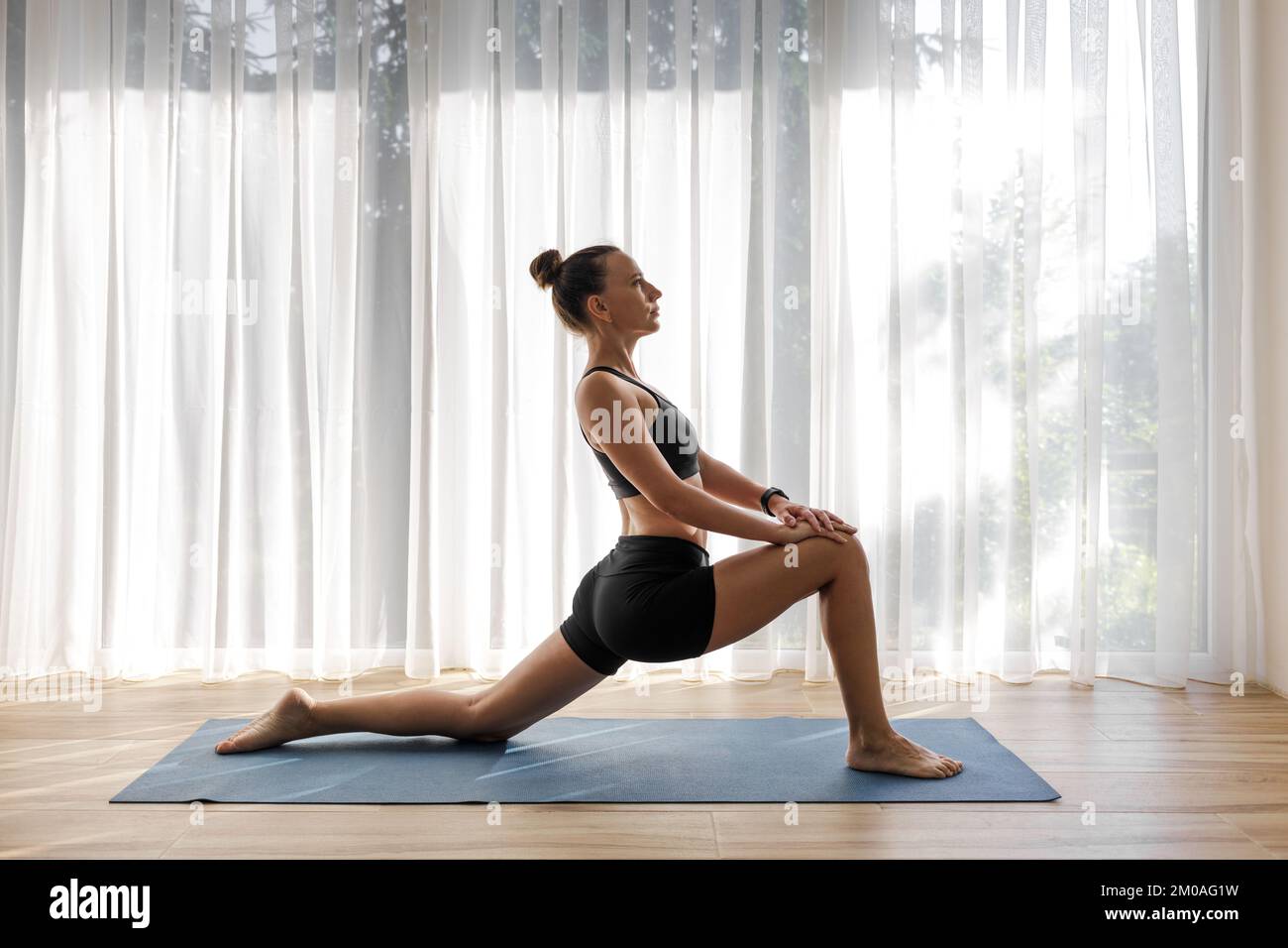 Giovane donna che fa la posa bassa di yoga di affondo durante l'addestramento di yoga di moring. Foto Stock