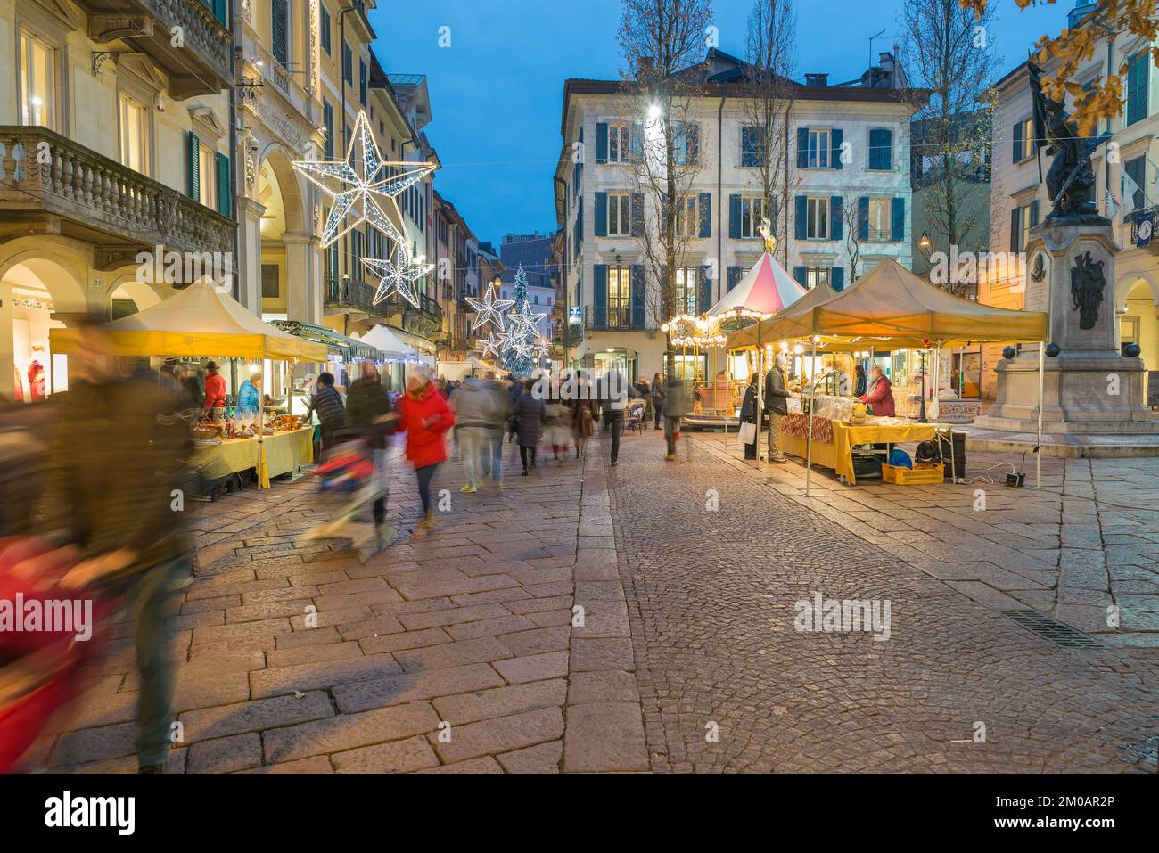 Shopping in un mercatino di natale di strada con le luci di festa al crepuscolo. Atmosfera natalizia nel centro storico di Varese Foto Stock