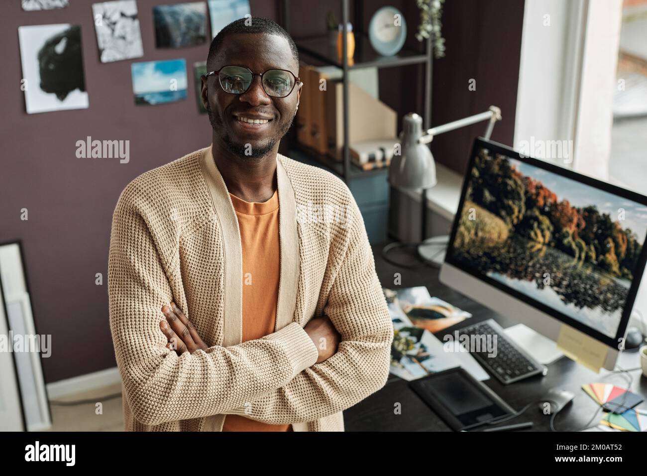 PORTRA di sorridente retoucher in piedi alla scrivania ufficio wh paesaggio foto sullo schermo Foto Stock