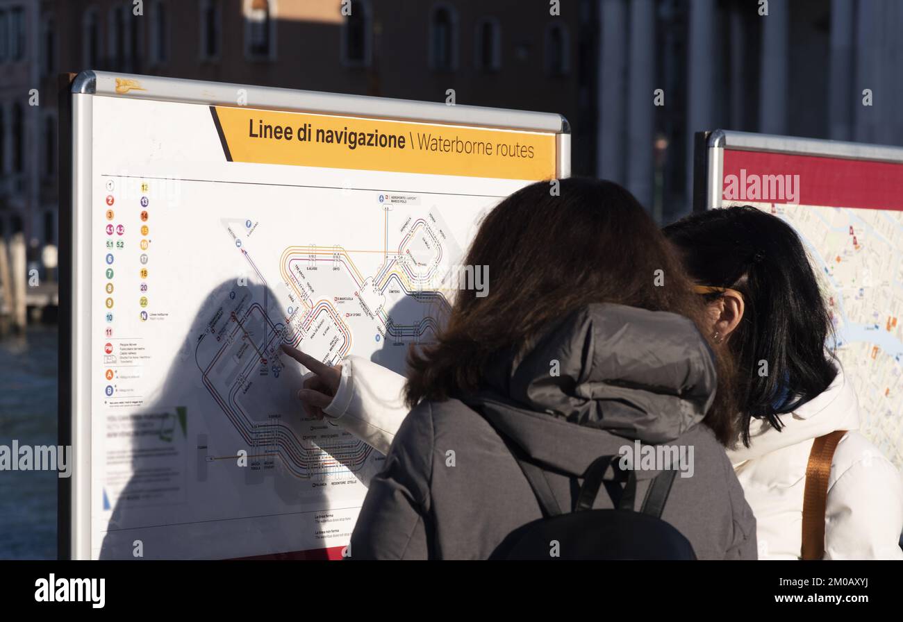 Due turisti femminili leggono la mappa di navigazione mentre scelgono le opzioni di itinerario a Venezia. Testo: ' Linee di navigazione', lingua italiana Foto Stock