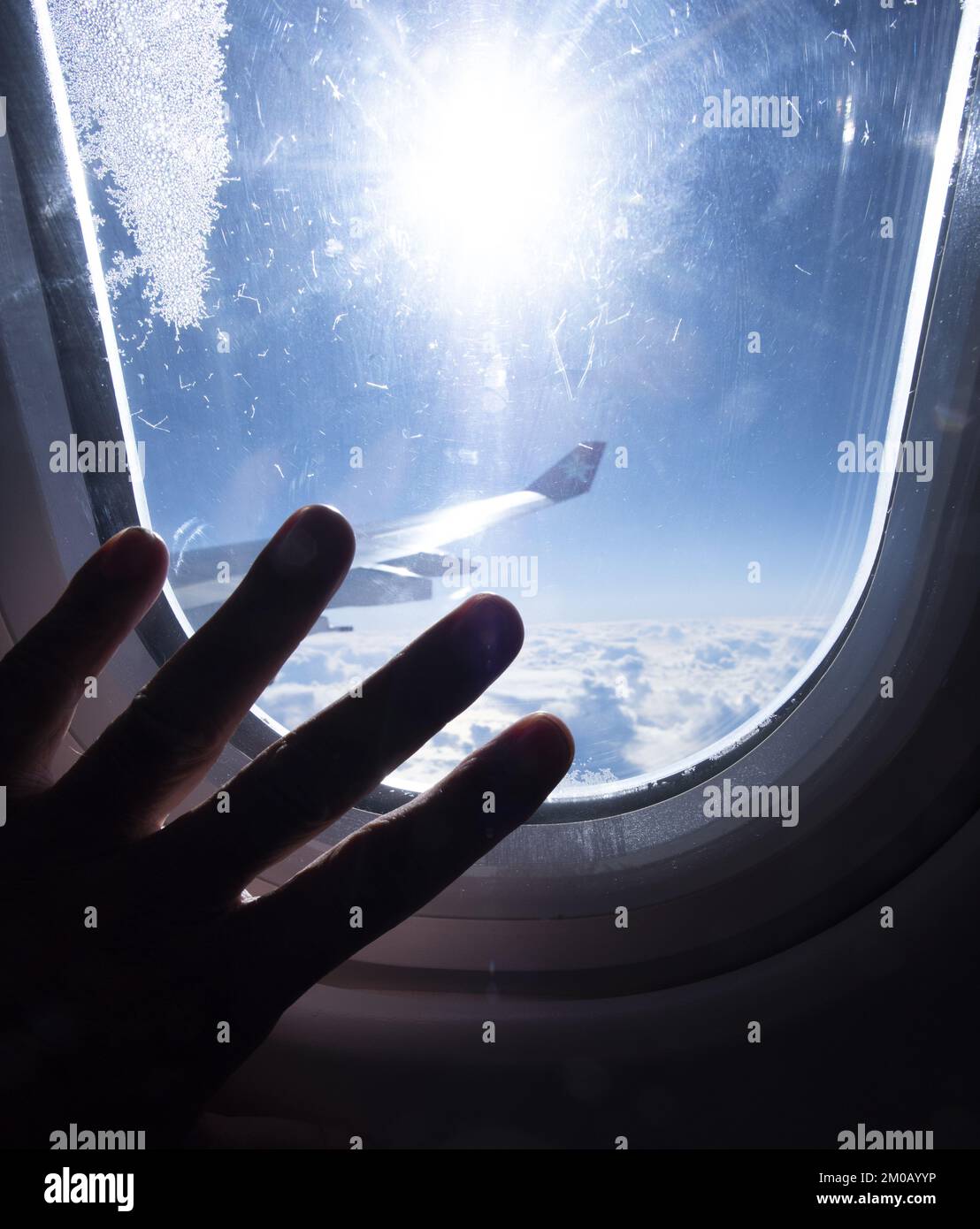 Dettaglio di una mano che tocca la finestra di un aereo in volo. Messa a fuoco selettiva Foto Stock