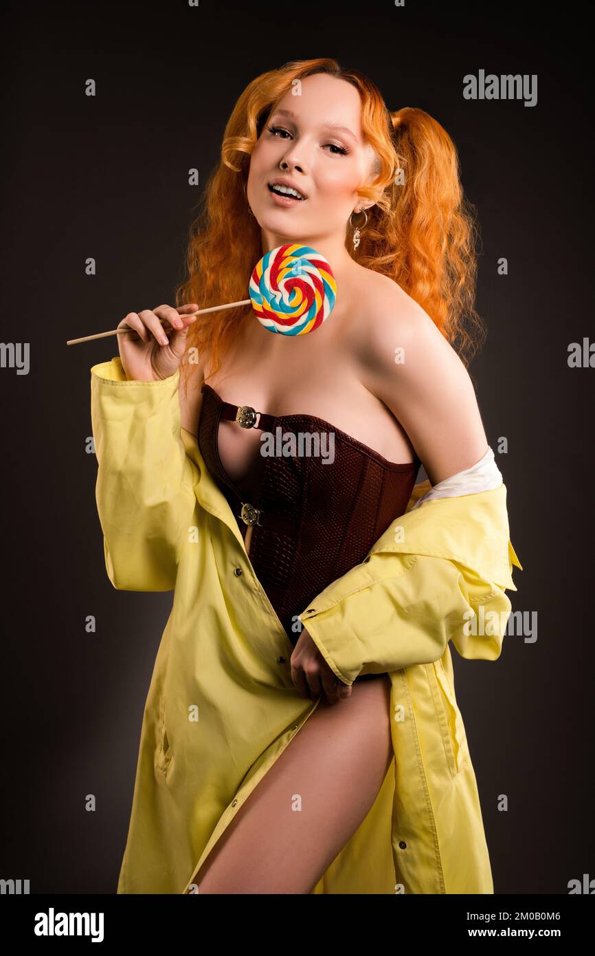 Modello femminile seducente con lollipop in mano sorridente alla fotocamera Foto Stock