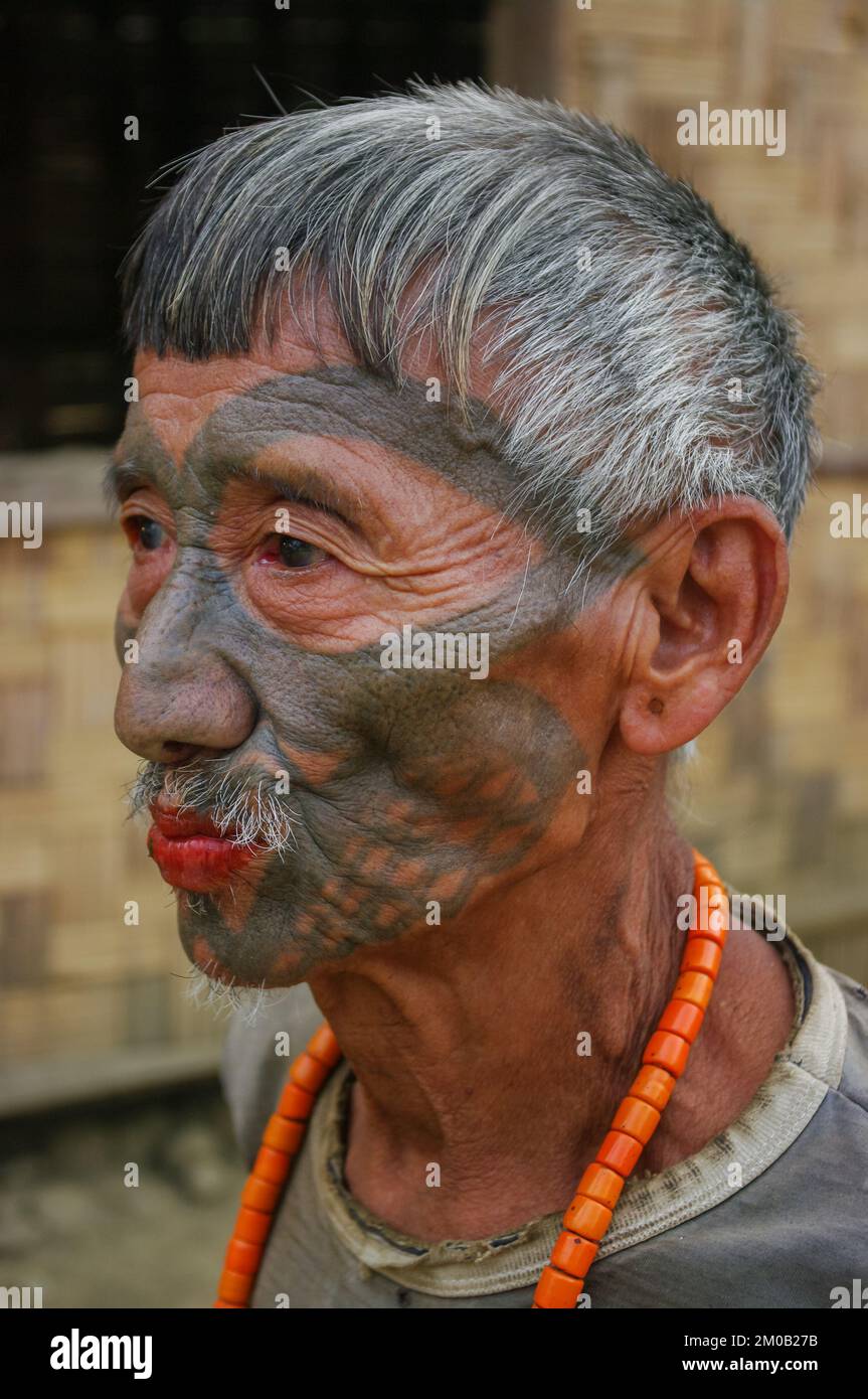 Mon District, Nagaland, India - 03 09 2014 : ritratto della vecchia tribù Naga Konyak cacciatore guerriero testa con tatuaggio facciale tradizionale e collana corallo Foto Stock