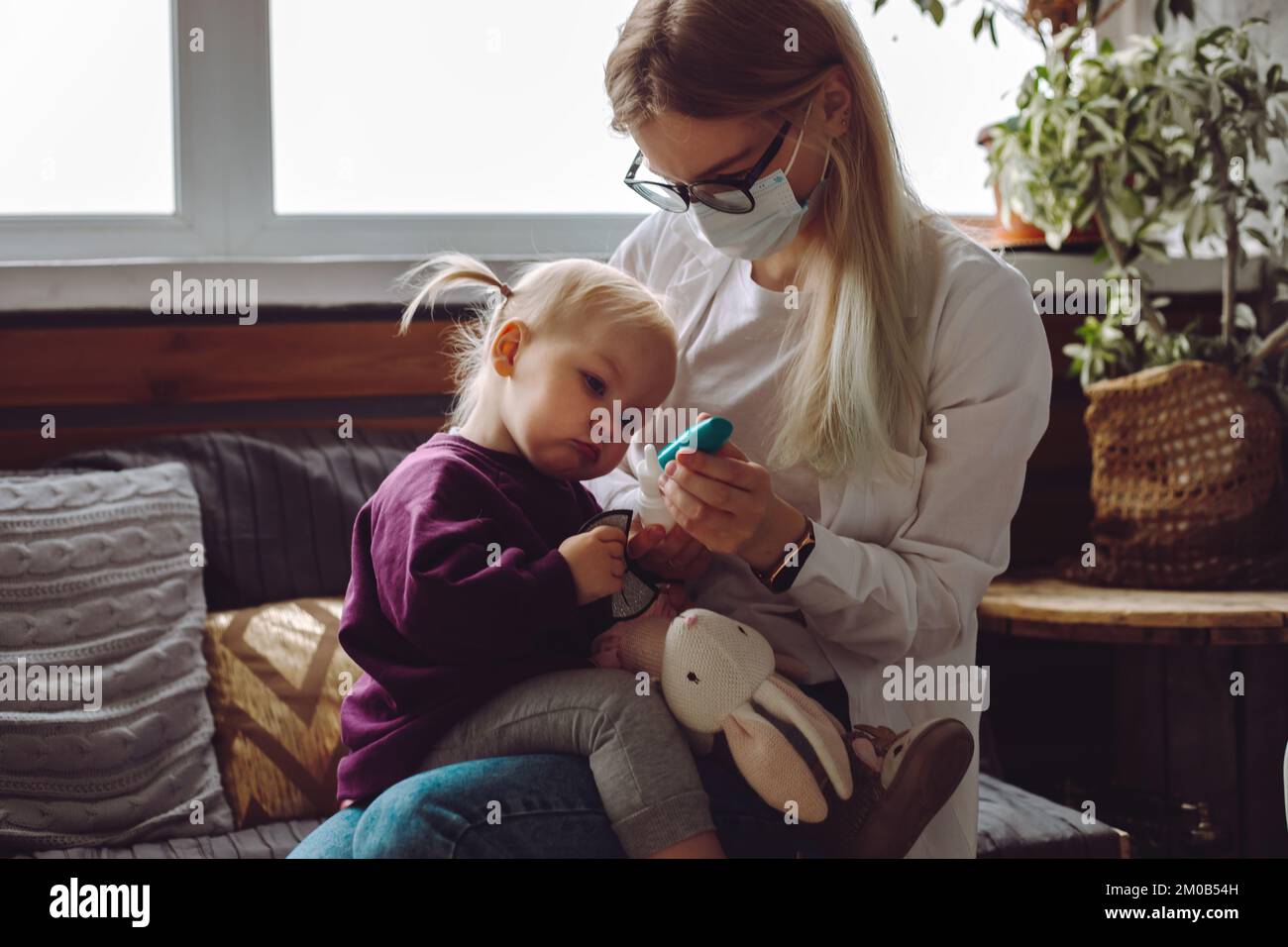Bambina seduta sul medico dei bambini, guardando la penna lancetta blu per il test di caduta del sangue concentrazione di glucosio. Foto Stock
