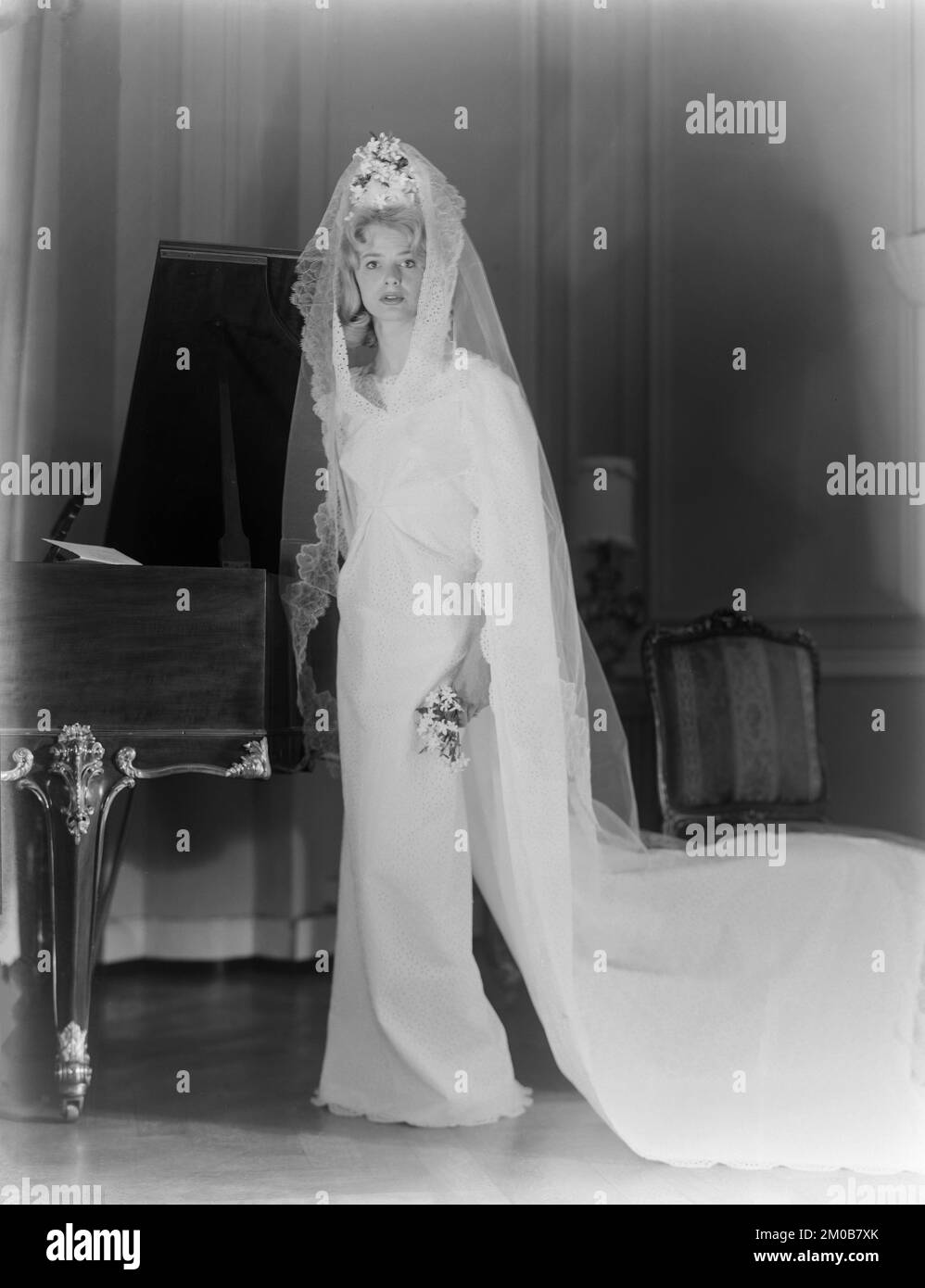 Un modello di moda 1960s, modellato un abito da sposa in uno studio a Londra, Inghilterra. Foto Stock