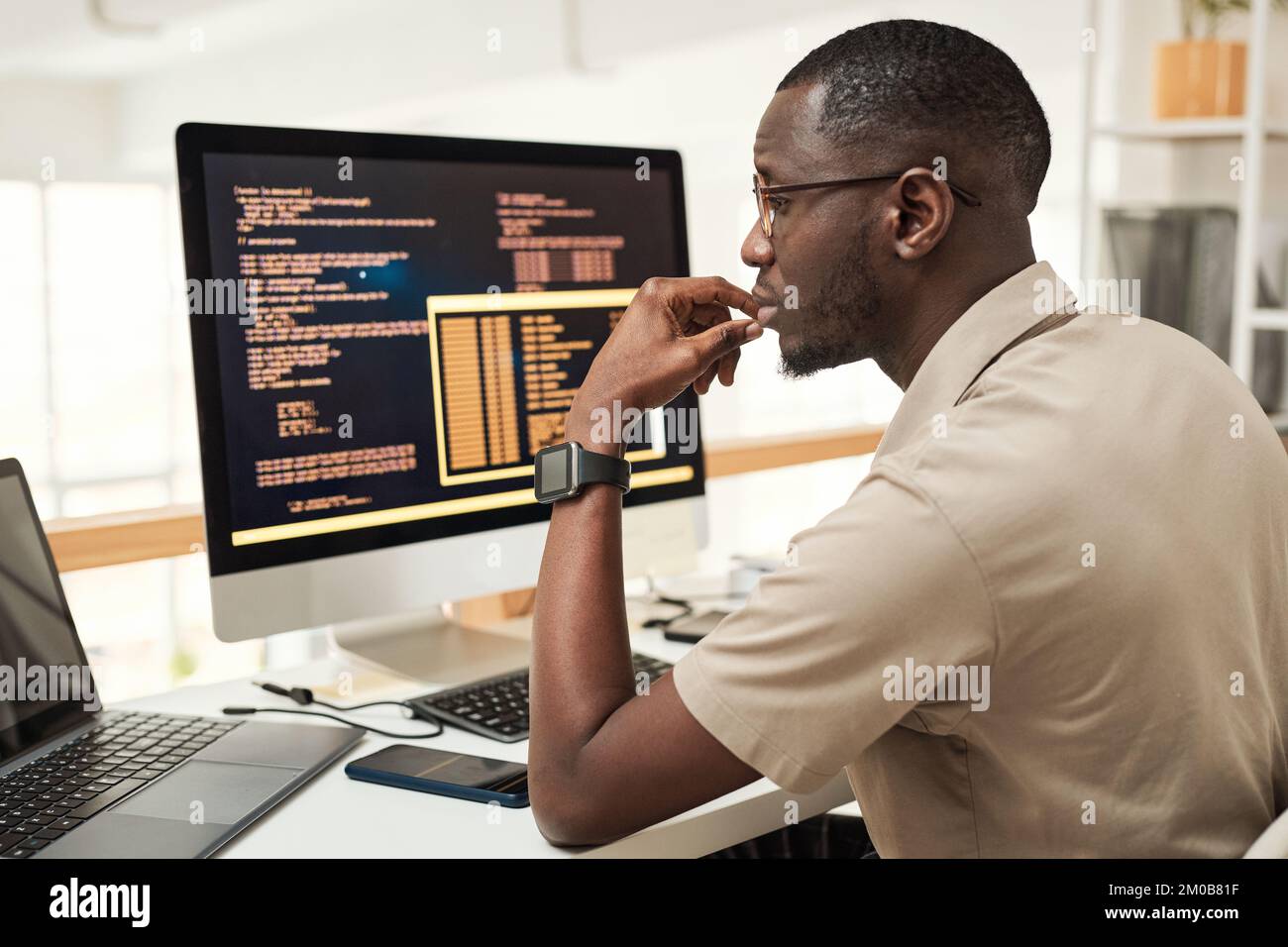 Il software engineer pensivo legge il codice di programmazione sullo schermo del laptop Foto Stock