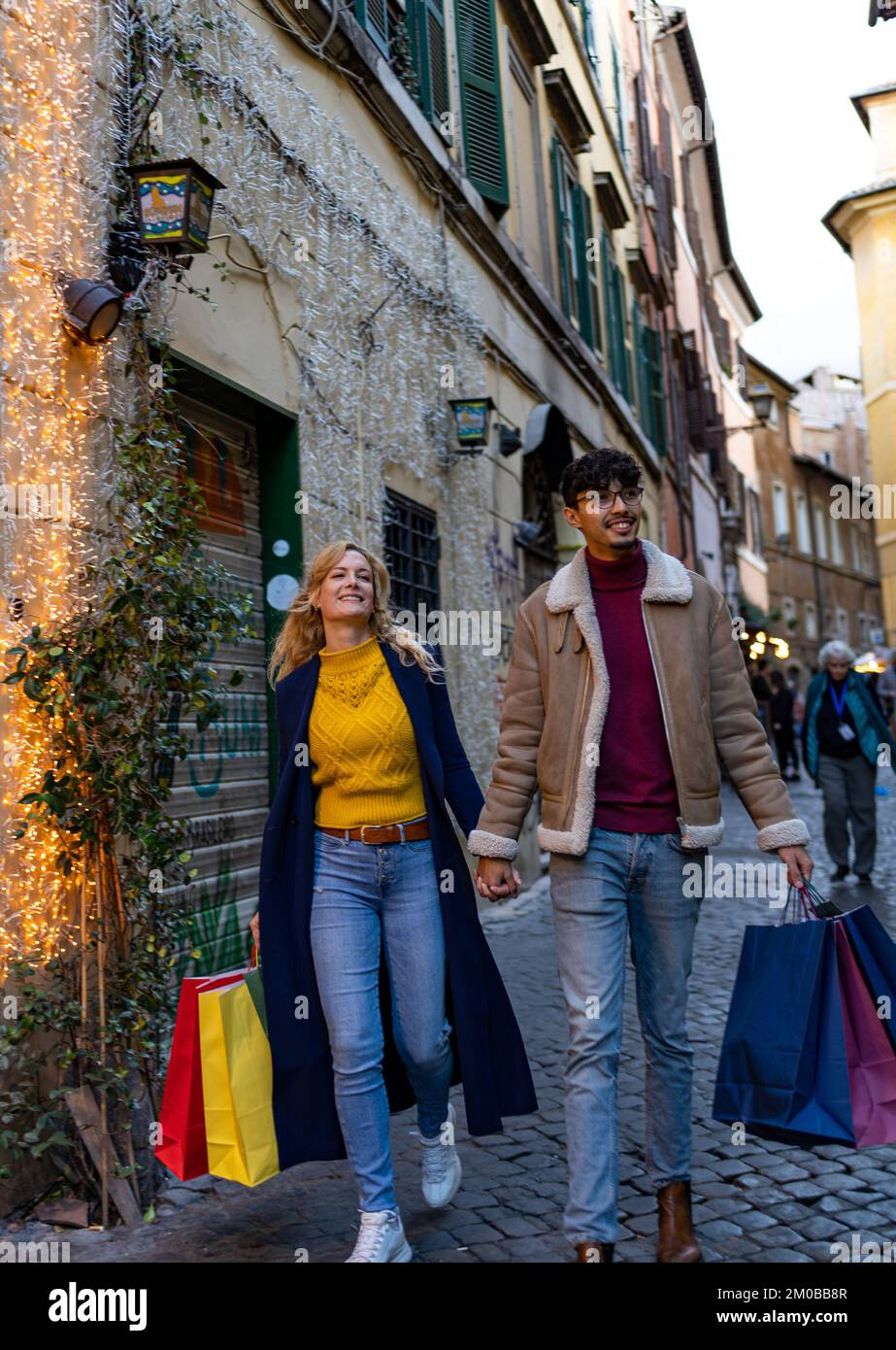 Giovane coppia multietnica che cammina per la città con borse per lo shopping Foto Stock