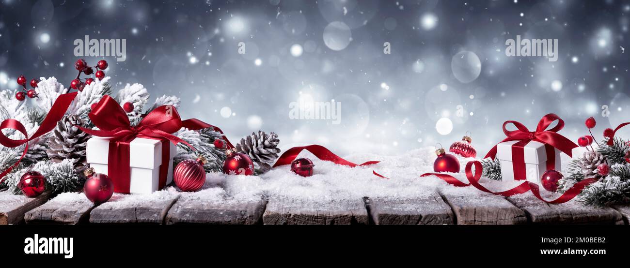 Regalo sulla neve su sfondo bianco d'inverno - regali con rami di abete e ornamenti rossi Foto Stock