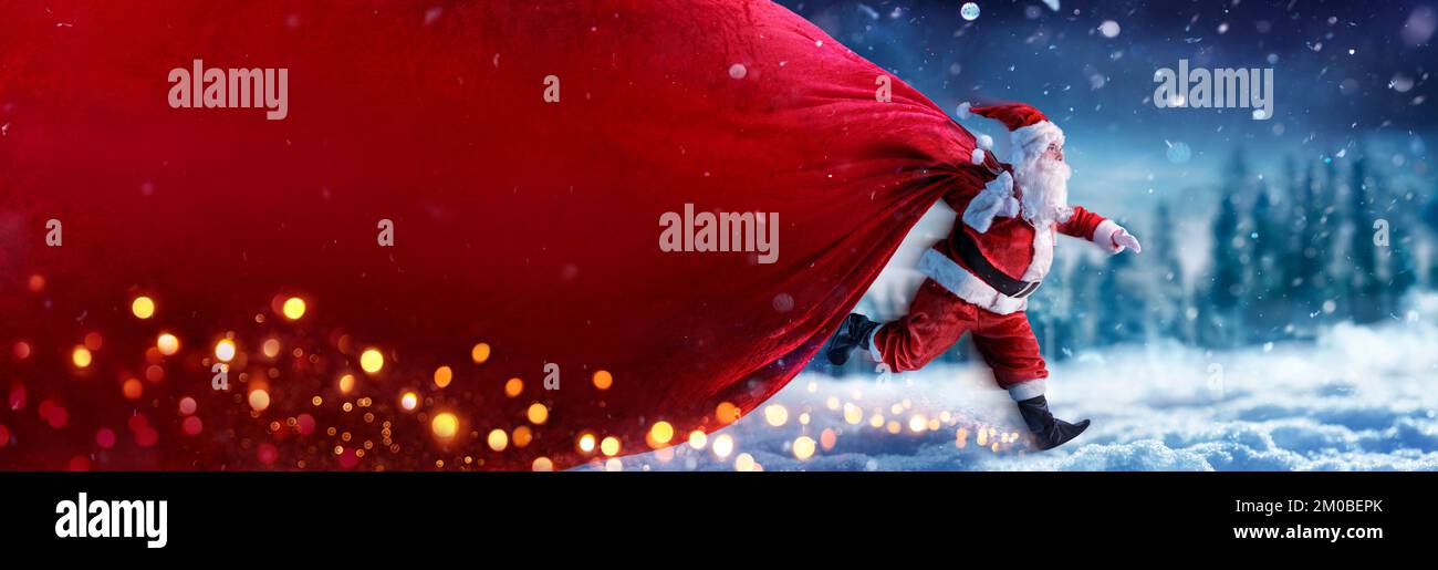 Babbo Natale con Banner Bag rosso in esecuzione sulla neve in inverno Paesaggio - consegna rapida presente Foto Stock