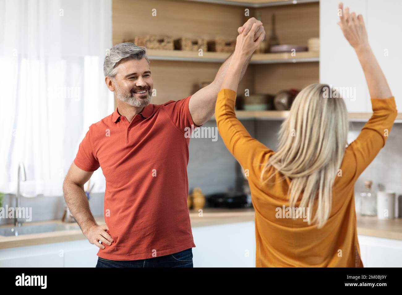 Allegro bello sposi di mezza età che ballano insieme in cucina Foto Stock