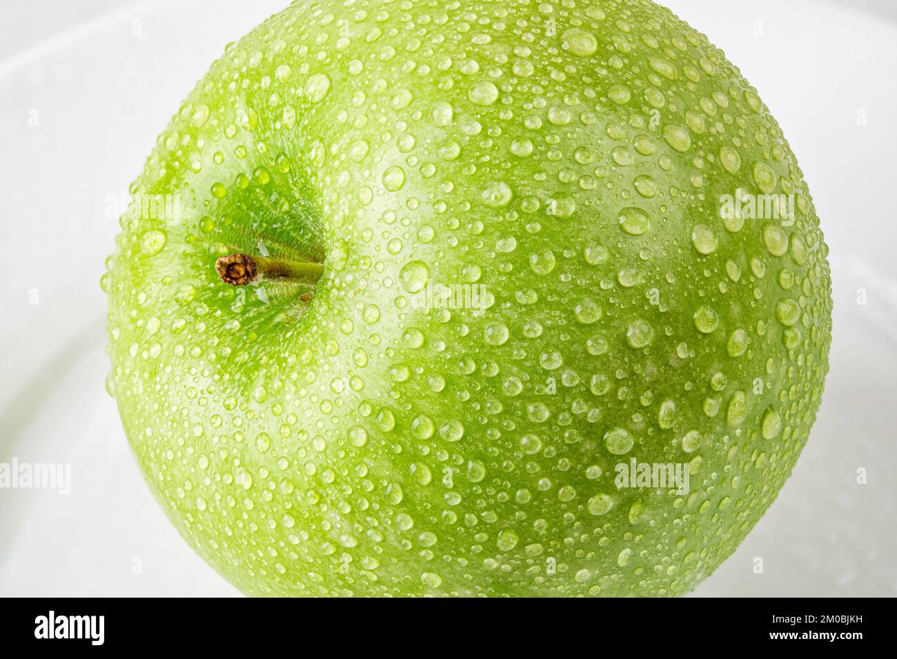 Mela verde fresca con gocce d'acqua macro. Primo piano di goccioline d'acqua sulla frutta biologica. Mela matura e succosa per uno spuntino vegetariano vitaminico. Primo piano. Foto Stock