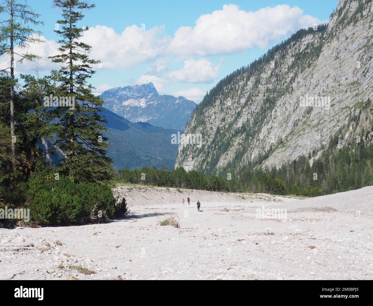 Un campo bianco con viaggiatori e alte montagne rocciose sullo sfondo Foto Stock