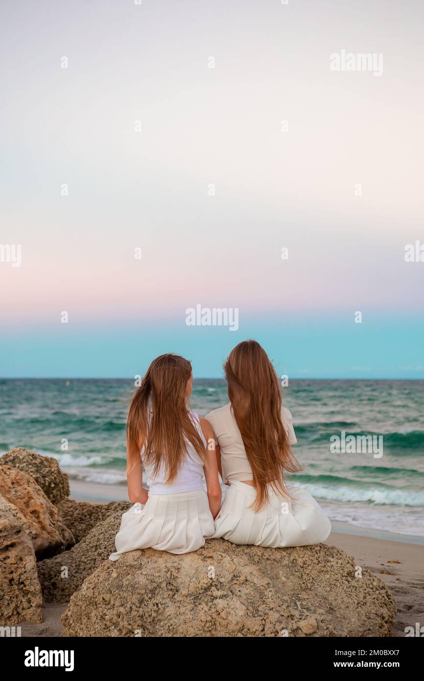 Adorabili ragazze con capelli lunghi godono della vista del mare sulla spiaggia al tramonto Foto Stock