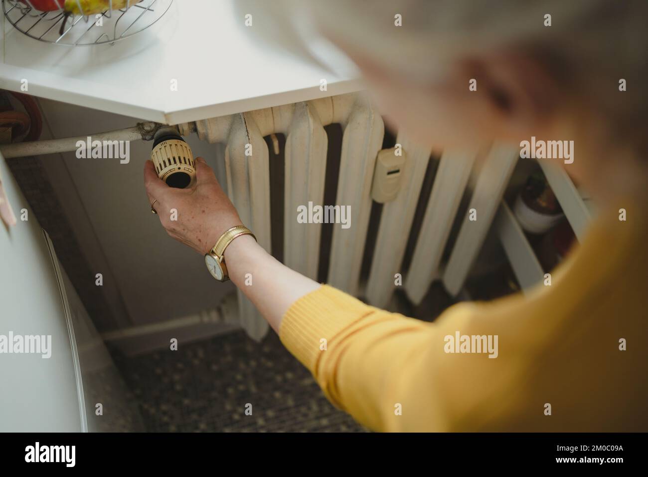 Donna che regola la temperatura di un radiatore a casa Foto Stock