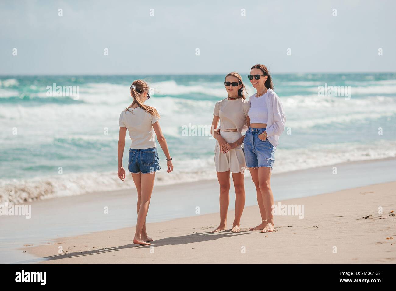 Adorabili poco ragazze e giovani madre tropicale sulla spiaggia di sabbia bianca Foto Stock