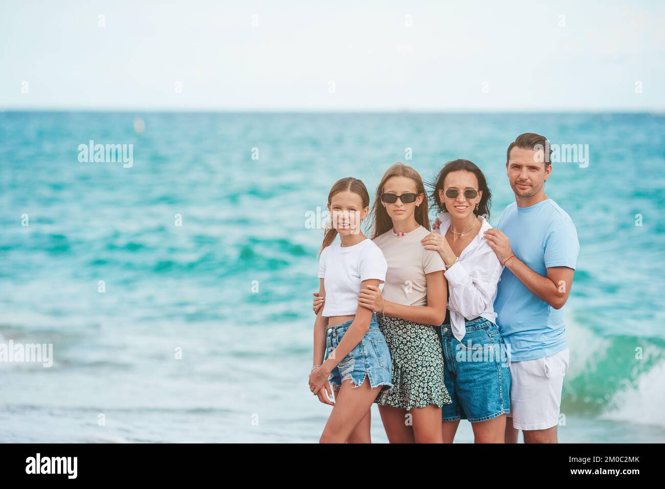 Felice famiglia in posa sulla spiaggia durante le vacanze estive Foto Stock