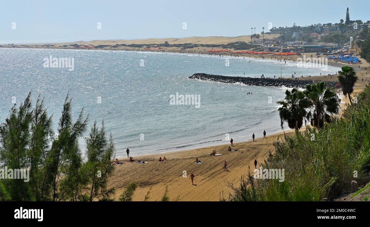 Playa El Veril spiaggia con i bagnanti sulla sabbia altri nel mare, San Agustín, Las Palmas, Gran Canaria. Dune di sabbia di Maspalomas in lontananza Foto Stock