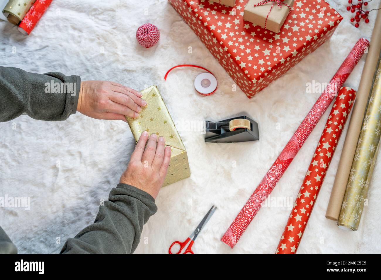 mani di donna adulta che avvolgono regali di natale sul tappeto a casa Foto Stock