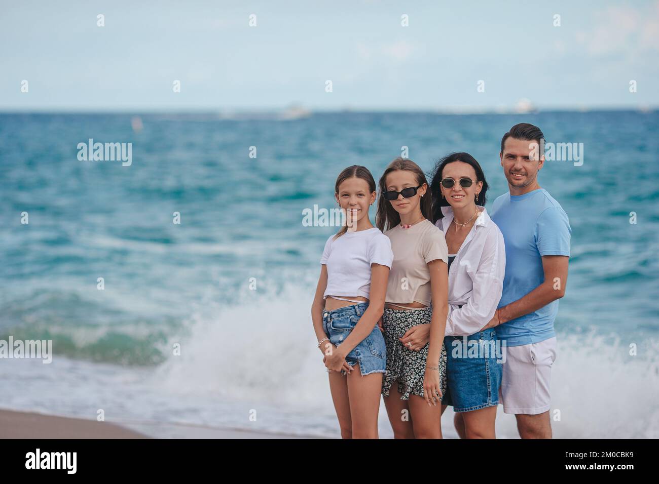 Felice famiglia in posa sulla spiaggia durante le vacanze estive Foto Stock