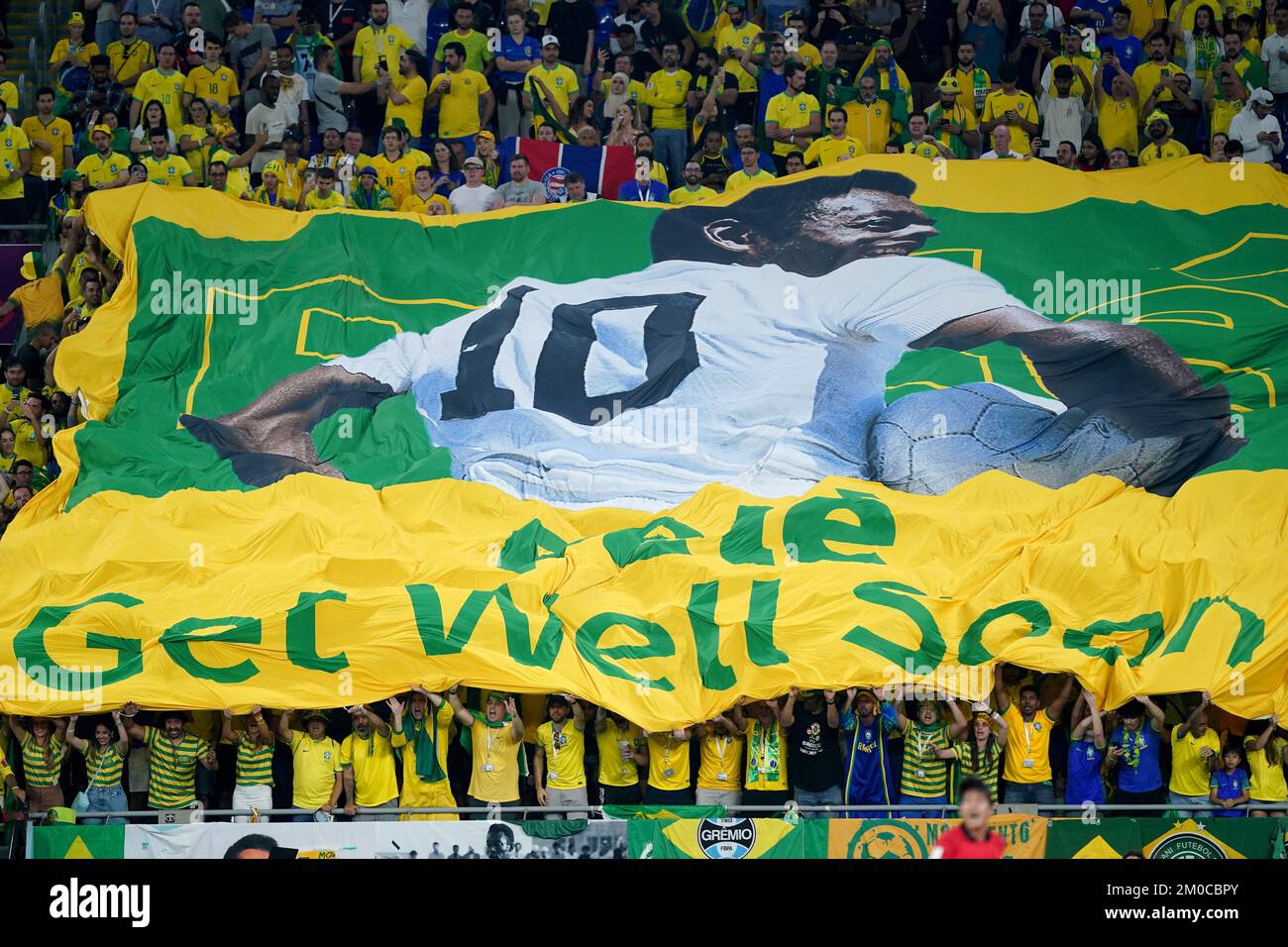 I tifosi brasiliani che si trovano in tribuna si augurano che l'ex giocatore Pele si allaccerà presto durante il round dei sedici campionati mondiali di calcio FIFA allo stadio 974 di Doha, Qatar. Data immagine: Lunedì 5 dicembre 2022. Foto Stock