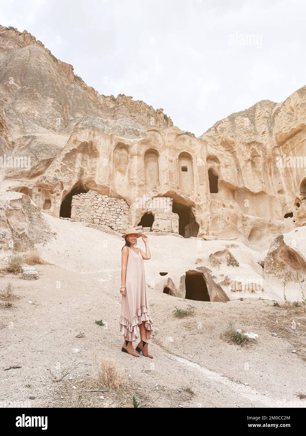 Felice giovane donna sullo sfondo di antiche formazioni rupestri in Cappadocia, Turchia. Il Monastero è uno dei più grandi edifici religiosi. Foto Stock