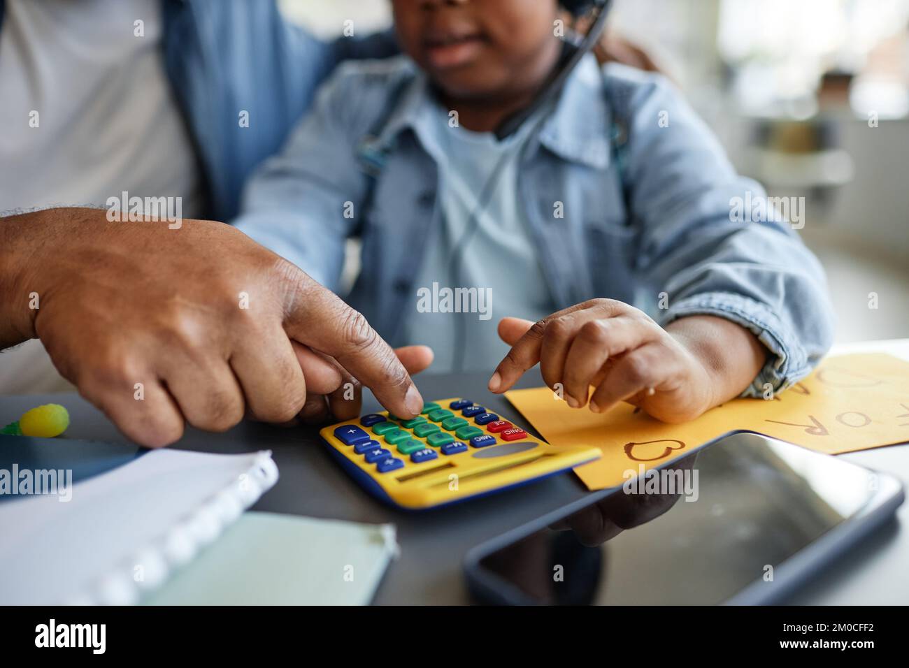 Primo piano di padre e bambino che giocano con la calcolatrice del giocattolo imparando a contare e lavorare Foto Stock